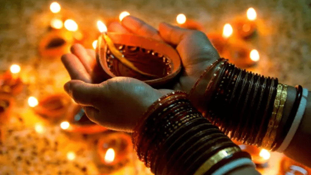 A lady wearing colourful bangles holding a earthen lamp 